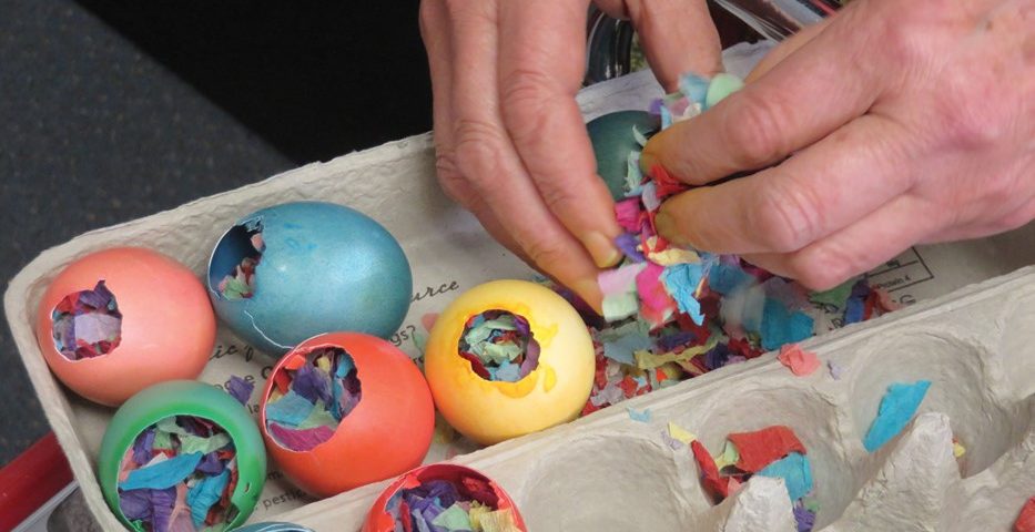 colored eggs in an egg carton with hands filling them with colorful scraps