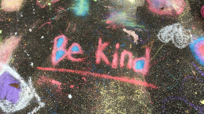 multicolord chalk art on asphalt that says Be Kind