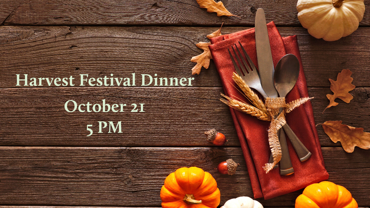 green text reading "Harvest Festival Dinner October 21 5 PM" on a dark wood background next to leaves, mini pumpkins, and a fork and napkin tied with twine
